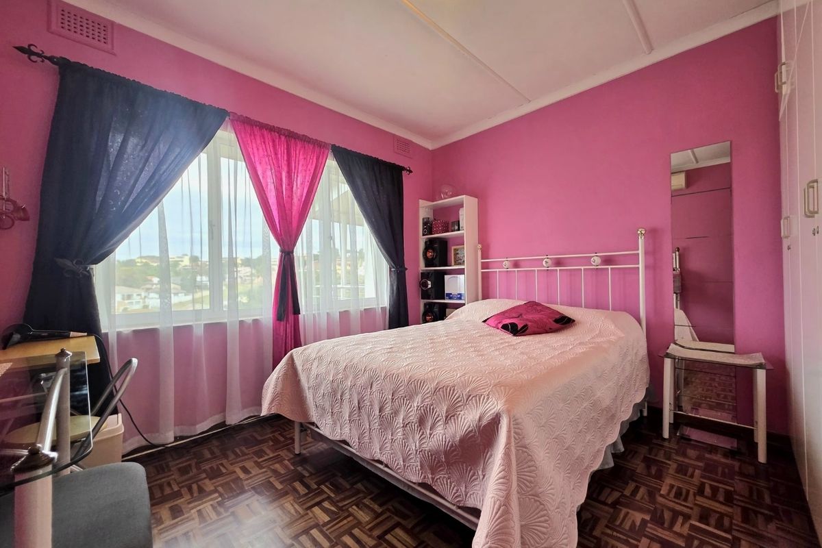 A bedroom featuring classic parquet flooring, built-in cupboards, and large windows that provide natural light and an elevated view.