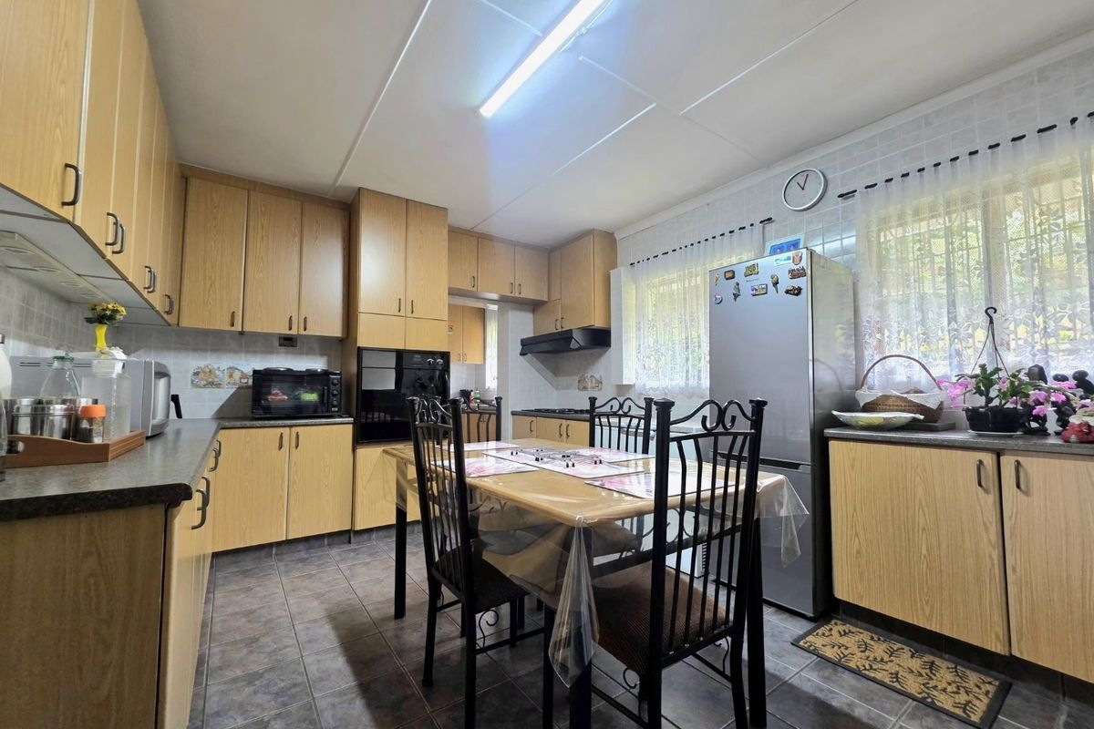 A functional kitchen featuring wood-look laminate cabinetry, tiled flooring, a built-in oven, and an integrated extractor fan with a dedicated dining area.