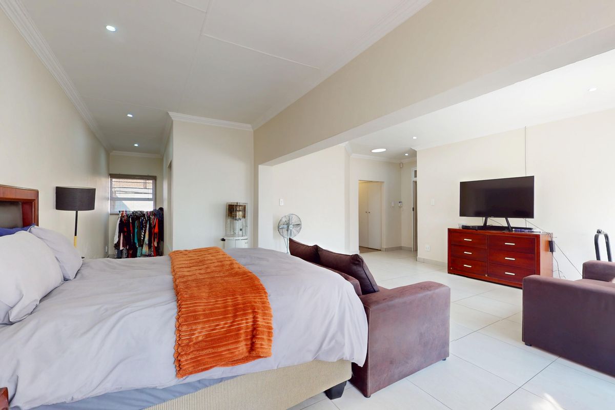Spacious bedroom featuring tiled flooring, recessed downlighting, and neutral wall finishes, offering a comfortable and well-lit living space.