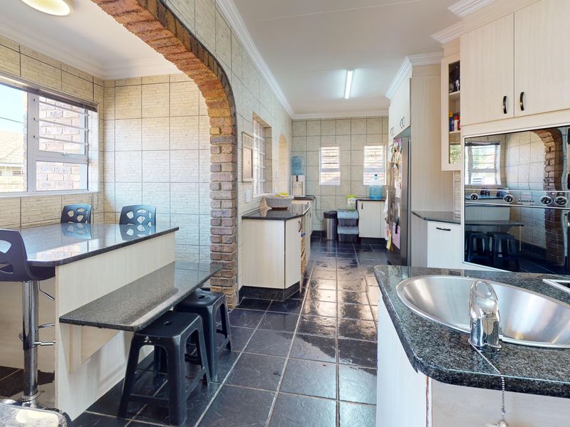 Spacious kitchen featuring granite countertops, built-in cabinetry, a built-in oven, and a distinctive brick archway, with tiled flooring throughout.