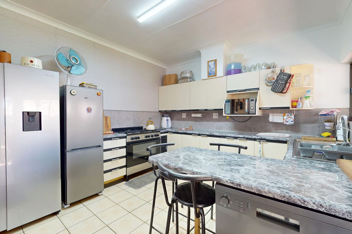 Functional kitchen featuring built-in cabinetry, gas stove, oven, and laminate countertops with tiled flooring.