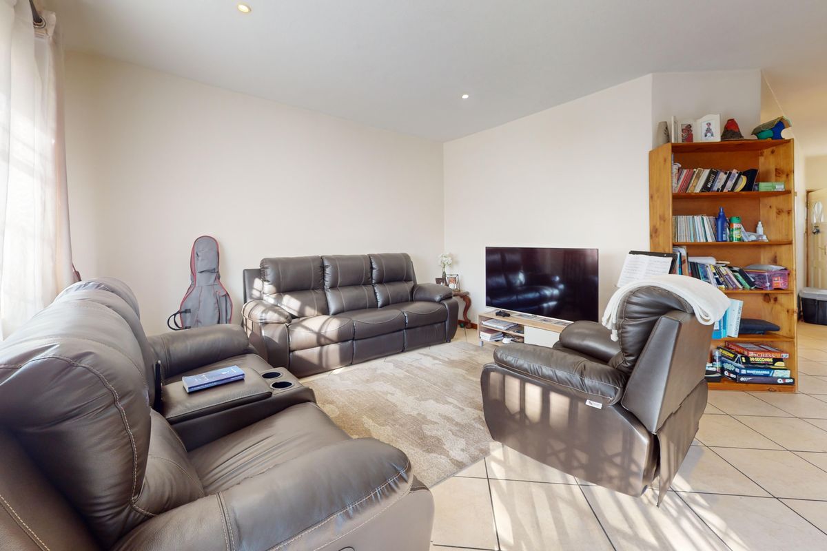 A comfortable living room featuring tiled flooring, recessed downlighting, and natural light from a large window, offering a functional and inviting space.