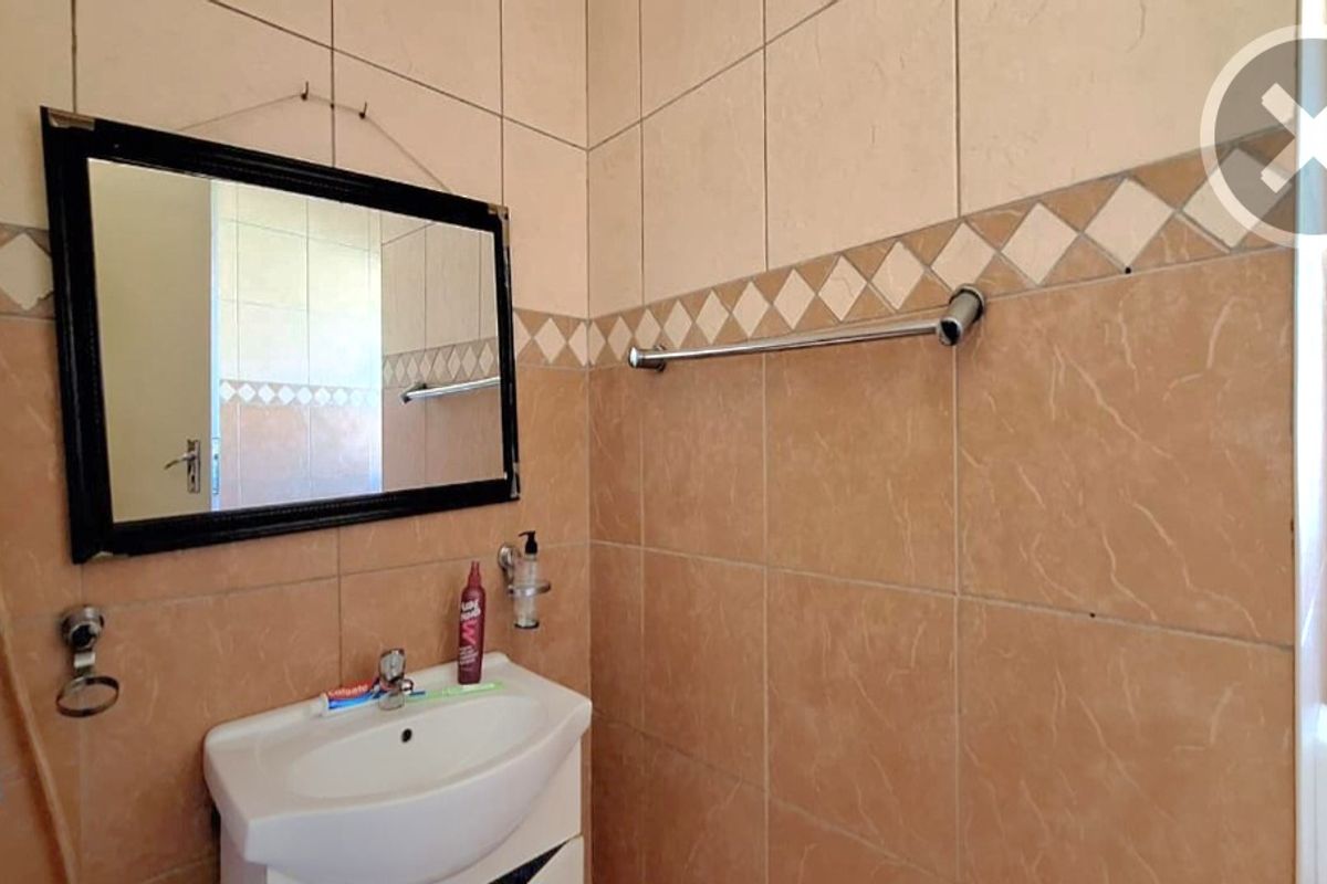 A functional bathroom featuring ceramic wall tiling, a pedestal basin with chrome mixer, and integrated shower plumbing.