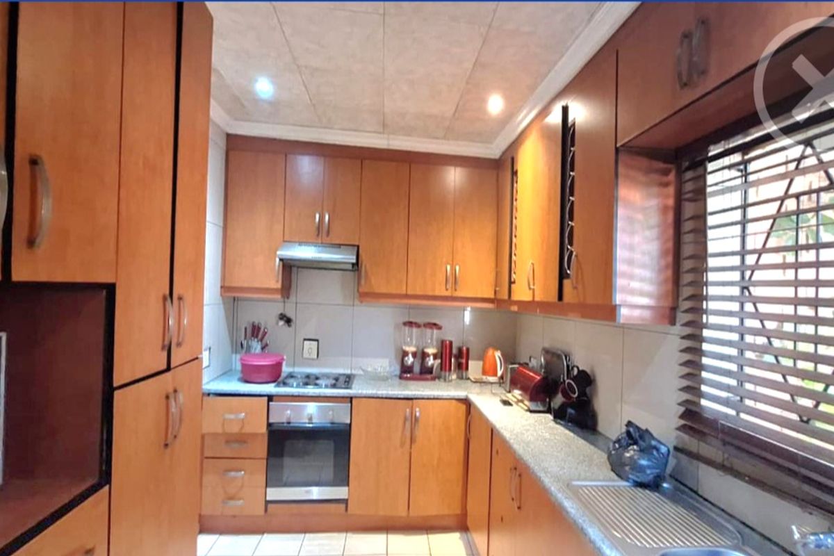 Functional kitchen featuring wood-finish cabinetry, built-in oven with gas hob, extractor fan, and tiled flooring with ample storage space.
