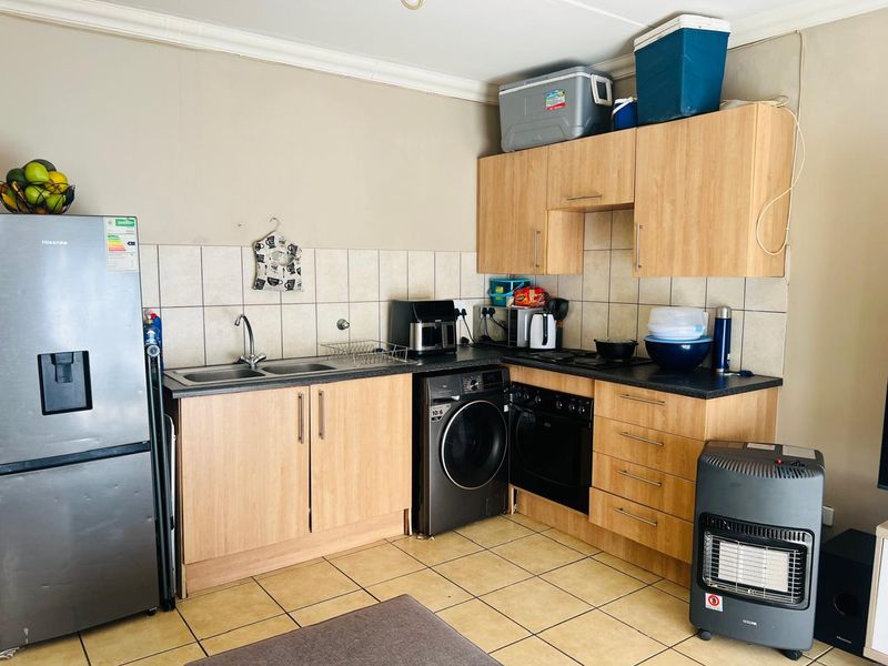 Compact kitchen featuring laminate cabinetry, tiled backsplash, built-in oven, hob, and integrated washing machine with tiled flooring.