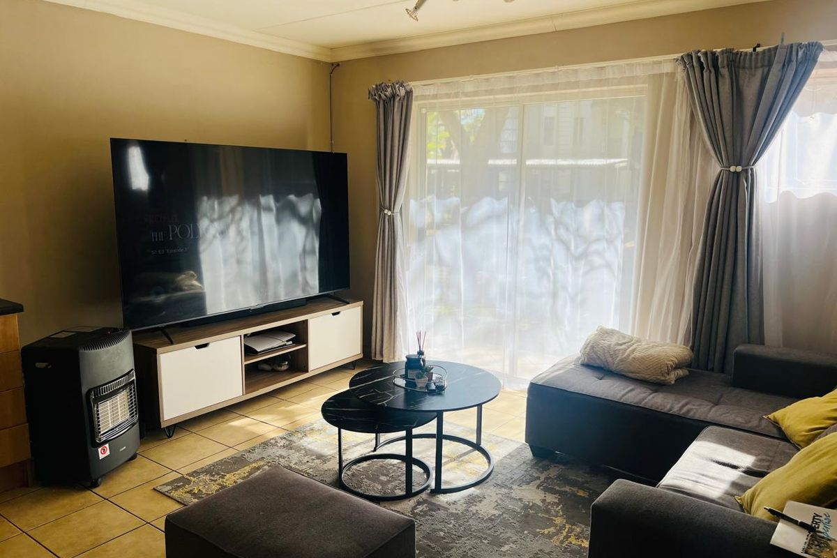 A living room featuring tiled flooring, coved ceilings, and a sliding glass door providing natural light.