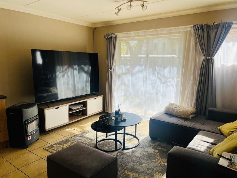 A living room featuring tiled flooring, coved ceilings, and a sliding glass door providing natural light.