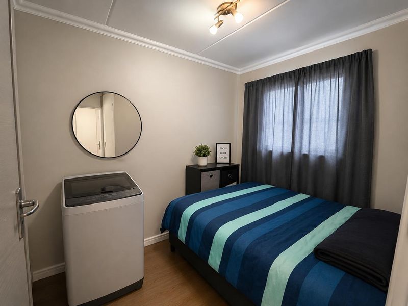 A well-maintained bedroom featuring laminate flooring, neutral wall tones, and classic ceiling cornicing, providing a comfortable and functional living space.