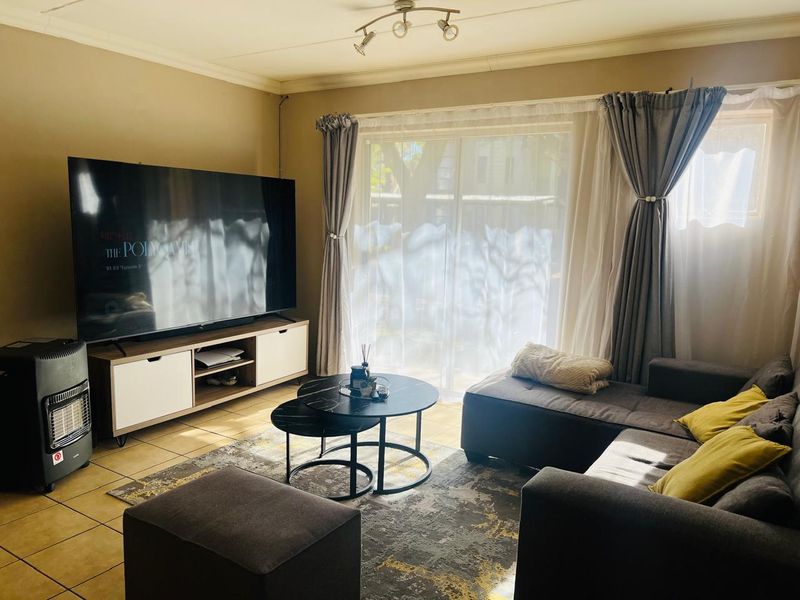 A comfortable living room featuring tiled flooring, coved ceilings, and a large sliding glass door that provides natural light.