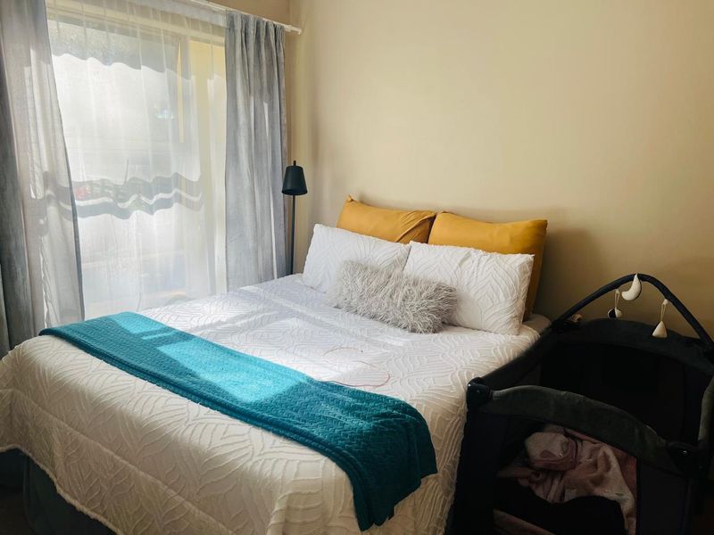 A bedroom featuring natural light from a window with installed curtain tracks.