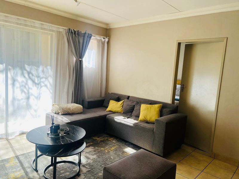A comfortable living room featuring tiled flooring and a large sliding glass door that provides natural light.