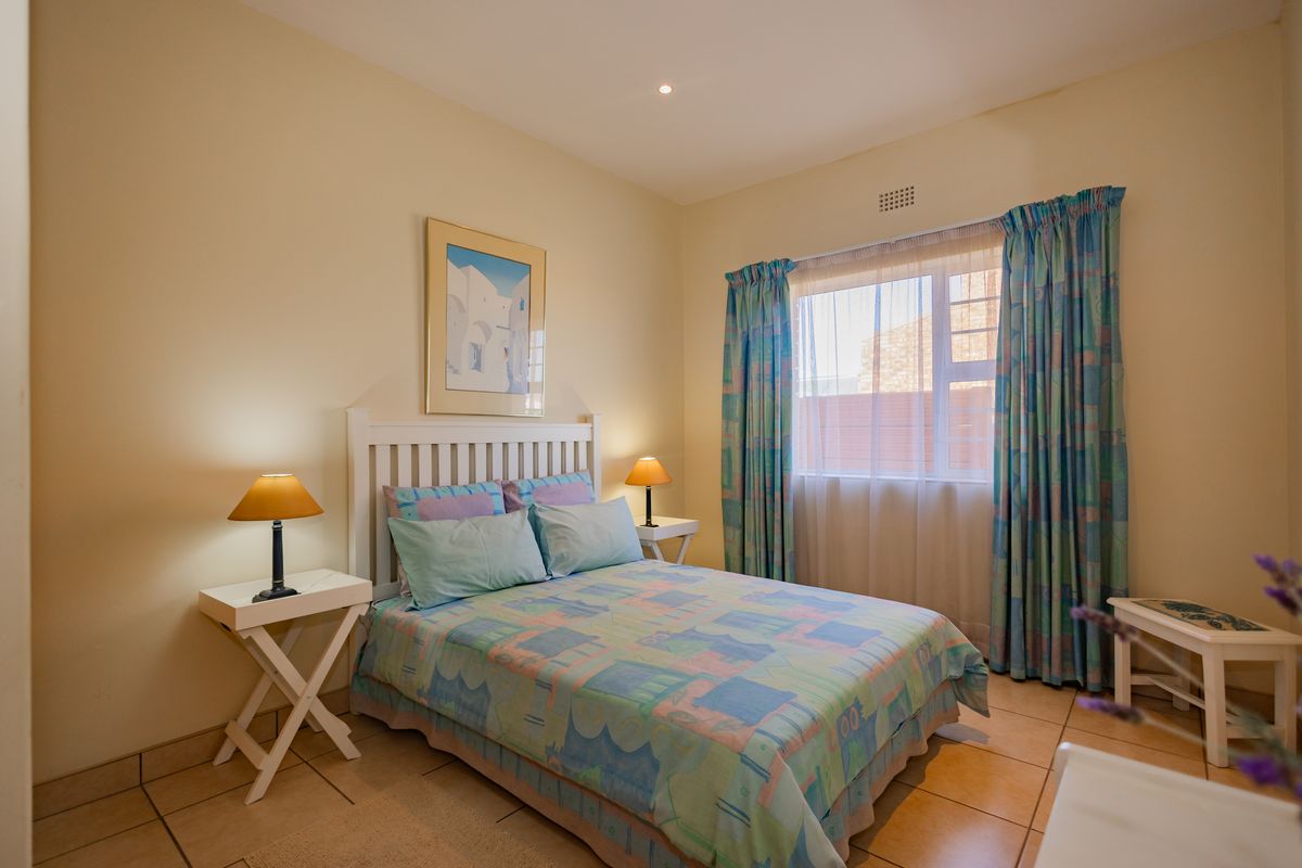 A well-lit bedroom featuring tiled flooring and a window with curtains, providing a comfortable and functional living space.