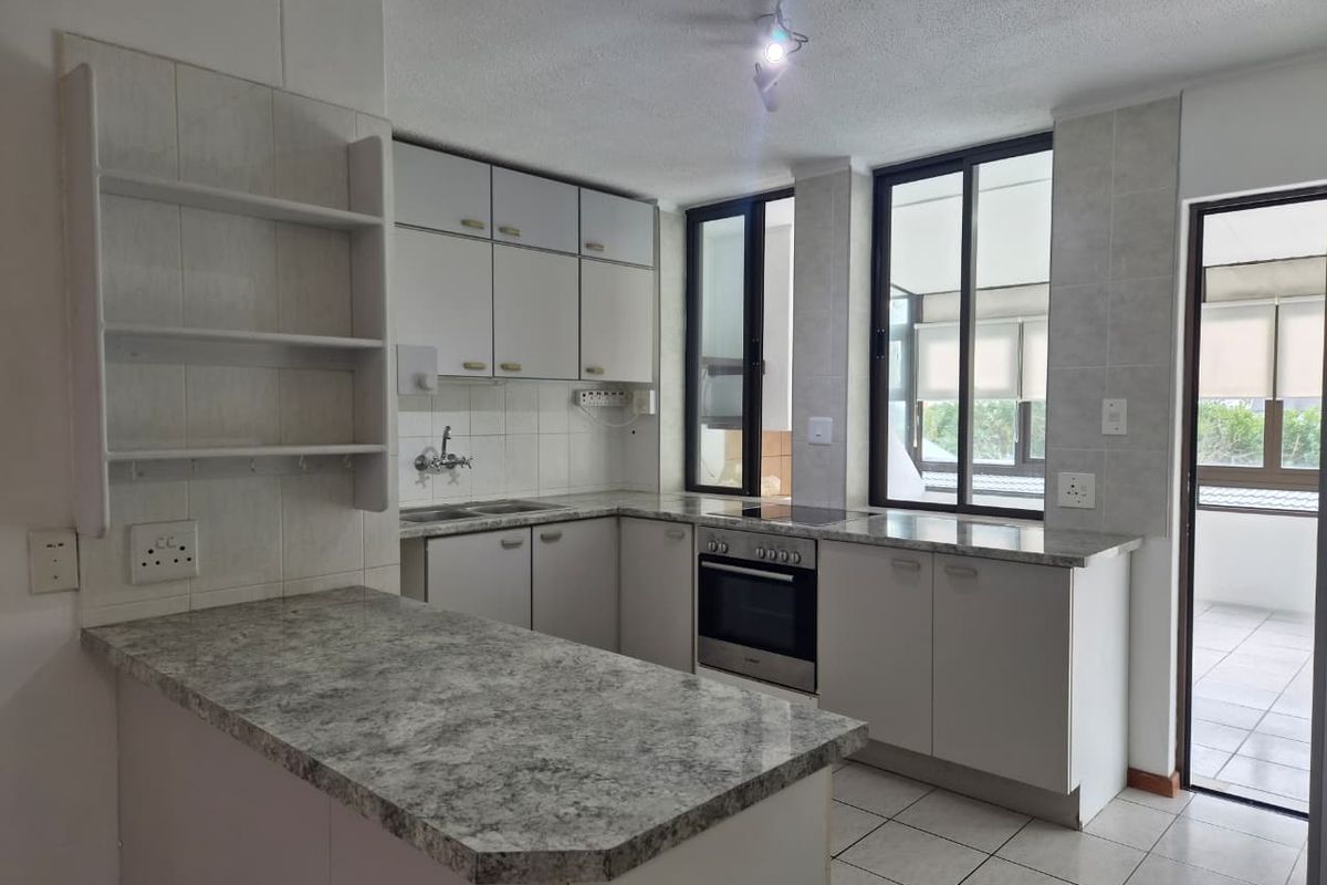 A functional kitchen featuring built-in cabinetry, laminate countertops, an integrated oven and hob, and direct access to an outdoor balcony area.