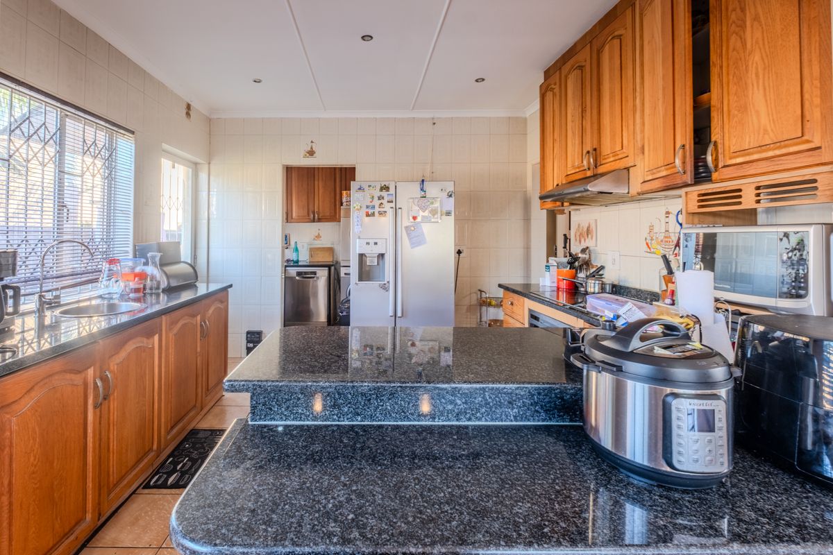 A functional kitchen featuring wooden cabinetry, granite countertops, a tiled backsplash, and integrated appliances, offering a practical layout for daily cooking and preparation.