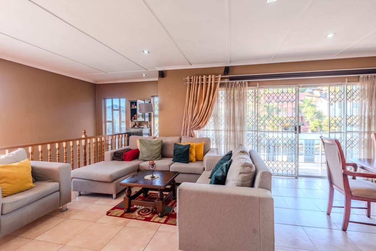 Spacious living area featuring tiled flooring, recessed lighting, and a sliding glass door with security gate leading to an outdoor space.
