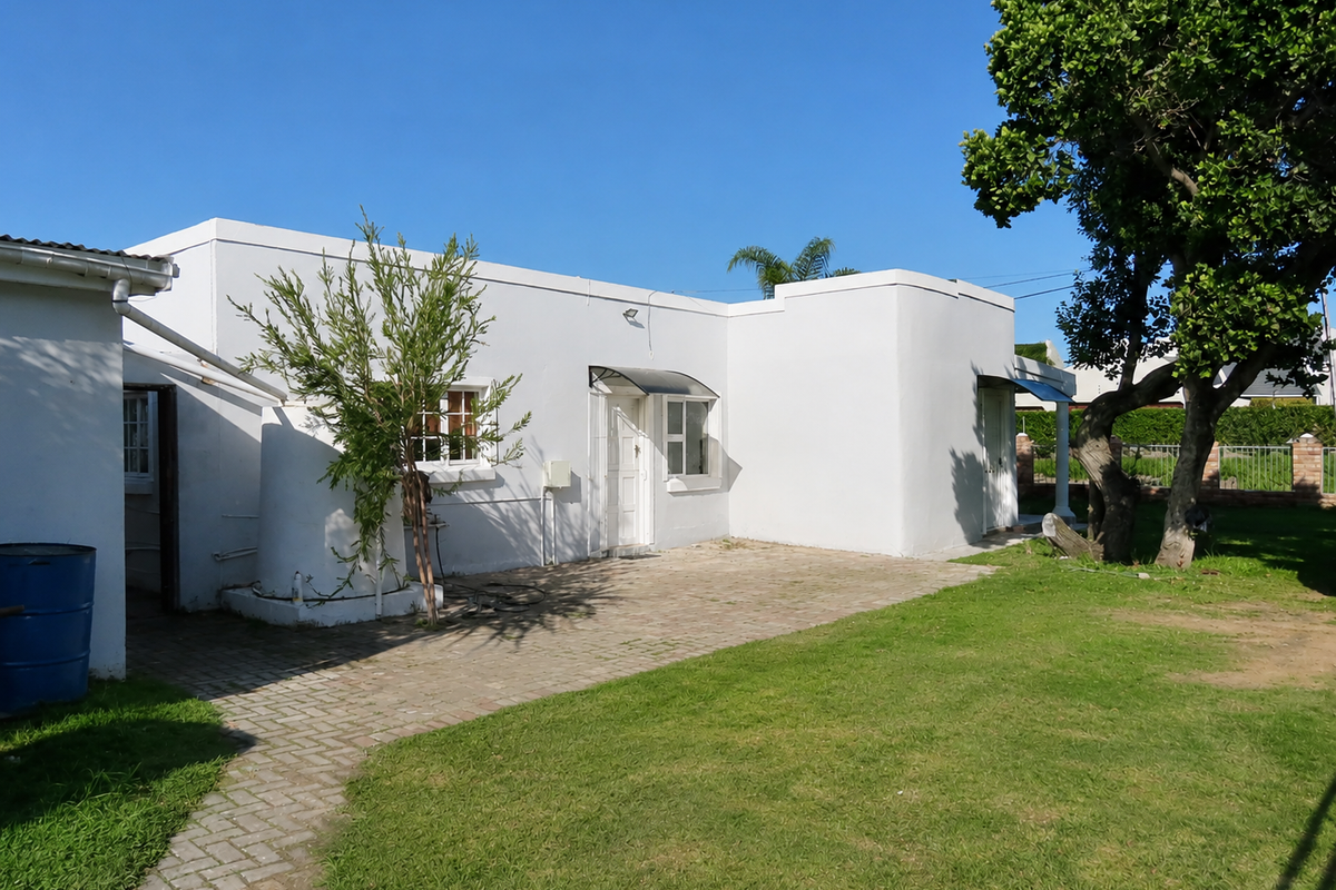 Rear view of the property featuring a paved patio area, established lawn, mature tree, and exterior wall access.