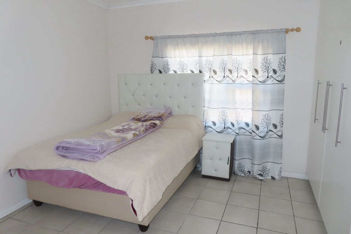 A functional bedroom featuring tiled flooring and built-in cupboards, providing a clean and neutral space ready for personalization.
