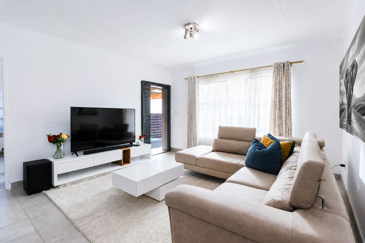 A bright and well-maintained living room featuring tiled flooring and direct access to an outdoor patio area.