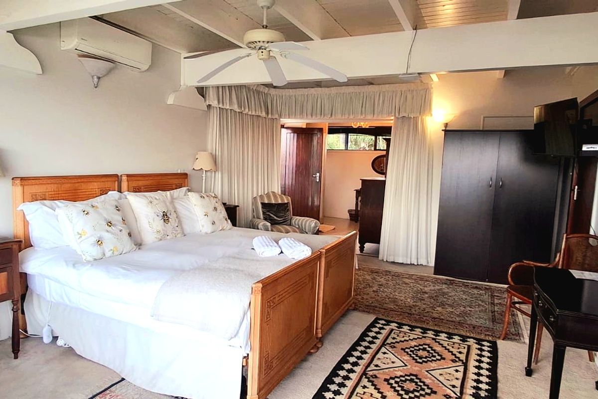 Spacious bedroom featuring exposed timber ceiling beams, a ceiling fan, and an integrated air conditioning unit.