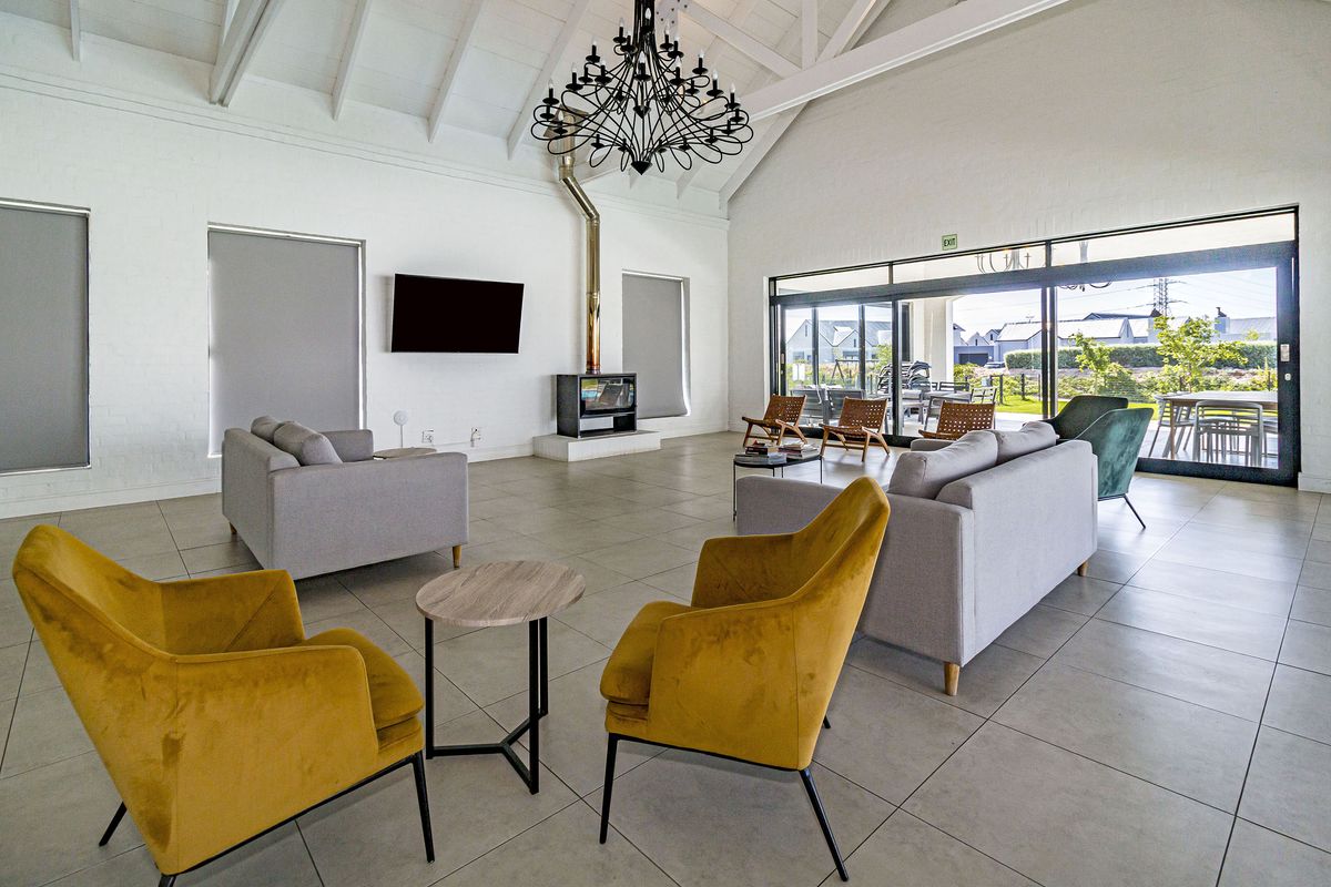 Spacious living room featuring a vaulted ceiling with exposed rafters, a modern freestanding fireplace, and large sliding glass doors leading to the patio.