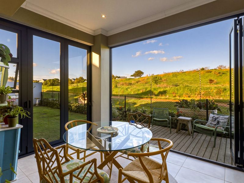 A bright, enclosed patio area featuring modern bi-fold doors that open onto a timber deck with scenic views.