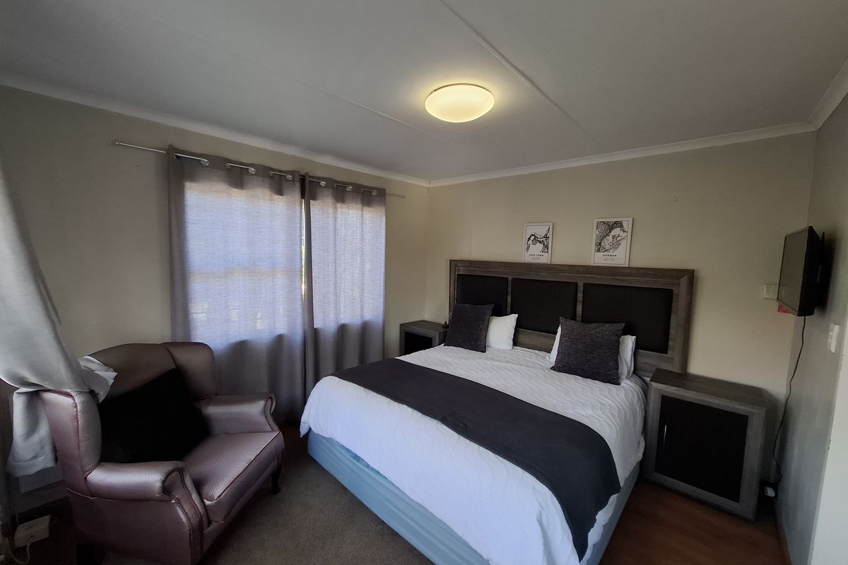 A well-proportioned bedroom featuring laminate flooring, neutral wall tones, and a central ceiling light fixture, offering a comfortable and functional living space.