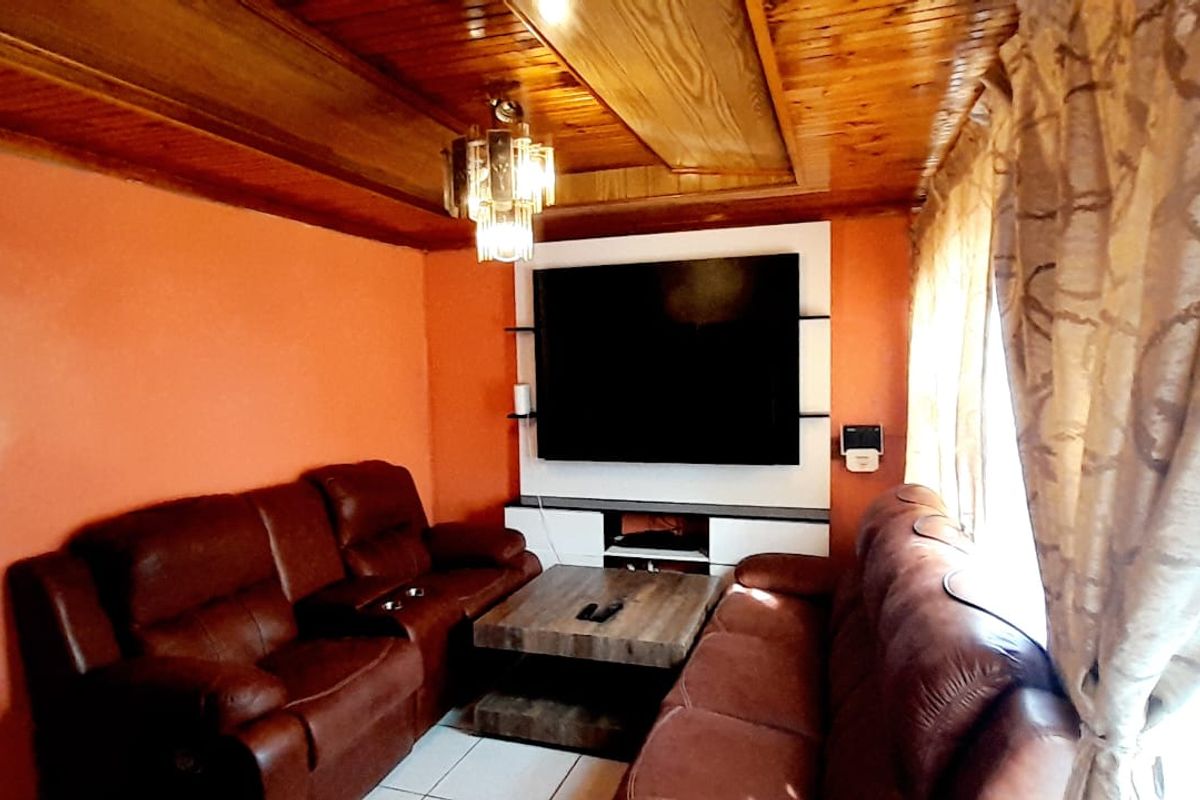 Living room featuring a timber tongue and groove ceiling, tiled flooring, and a built-in media unit.