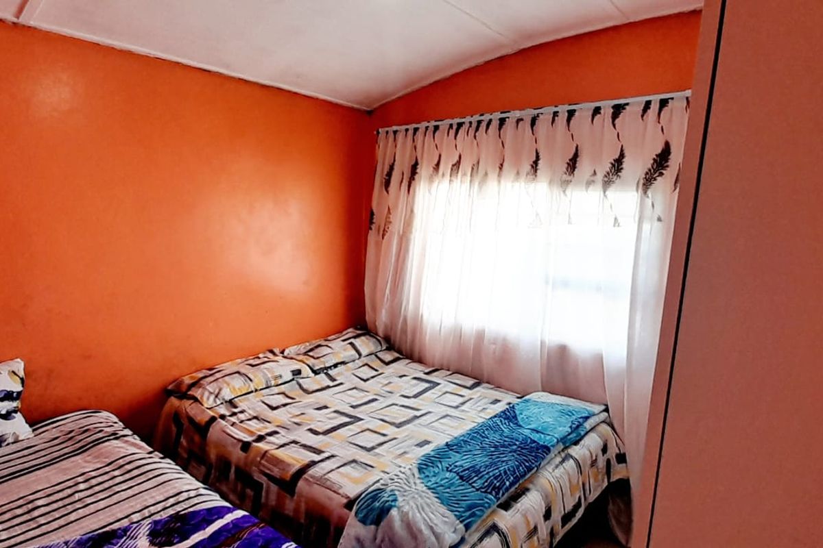 A bedroom featuring bright orange walls and a built-in wardrobe, offering a functional space that could benefit from modern updates and neutral styling.