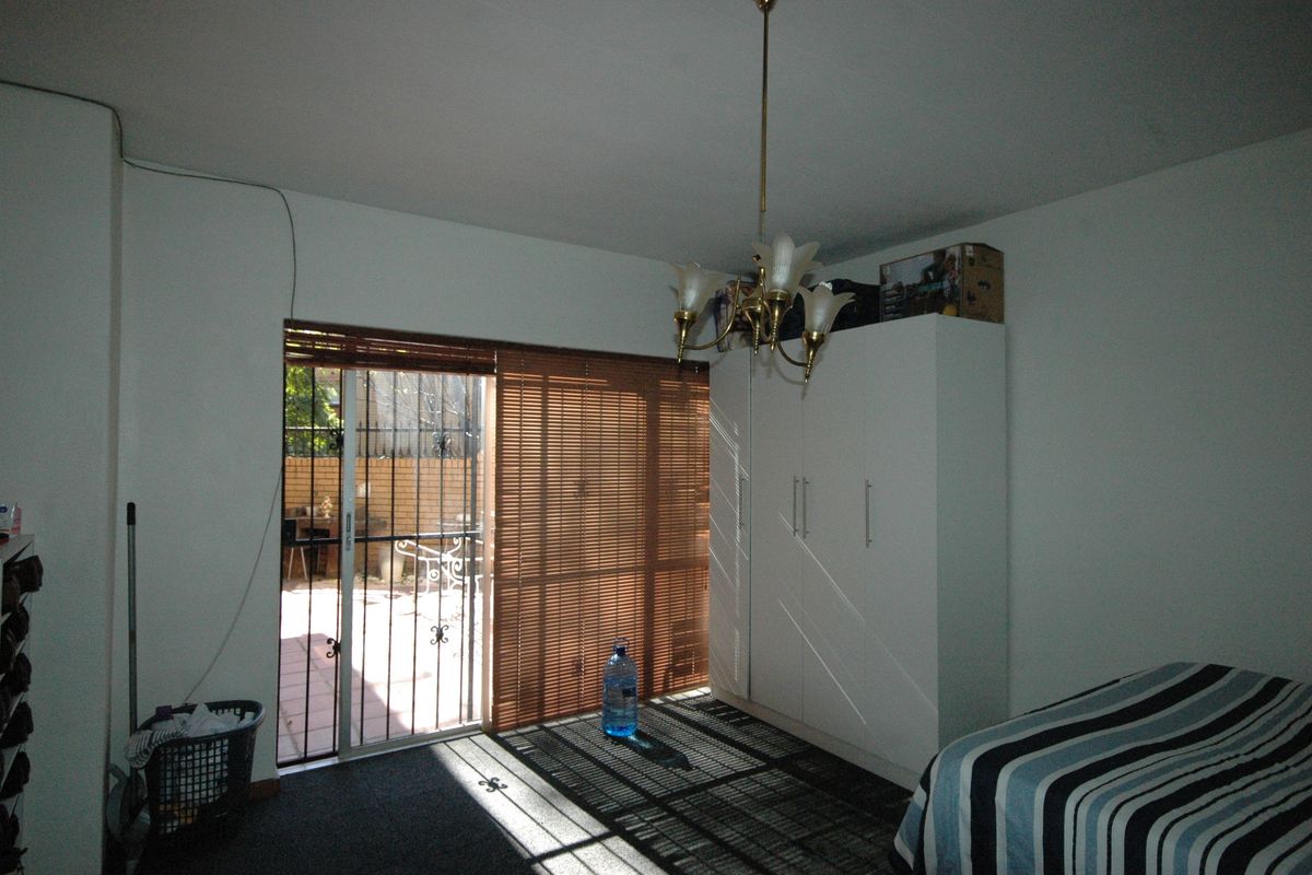 Bedroom featuring a built-in wardrobe, sliding glass door with security gate, and direct access to an outdoor patio area.