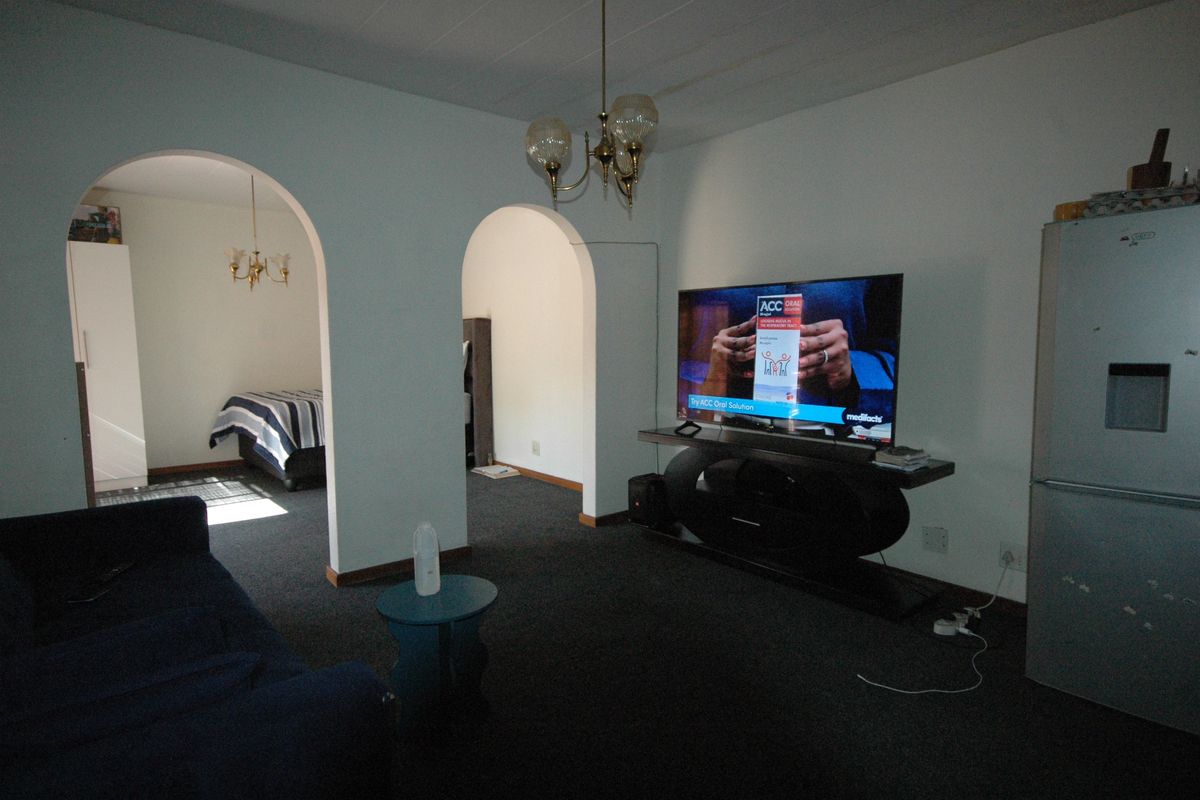 A living room featuring arched doorways leading to adjacent spaces, carpeted flooring, and a central ceiling light fixture.