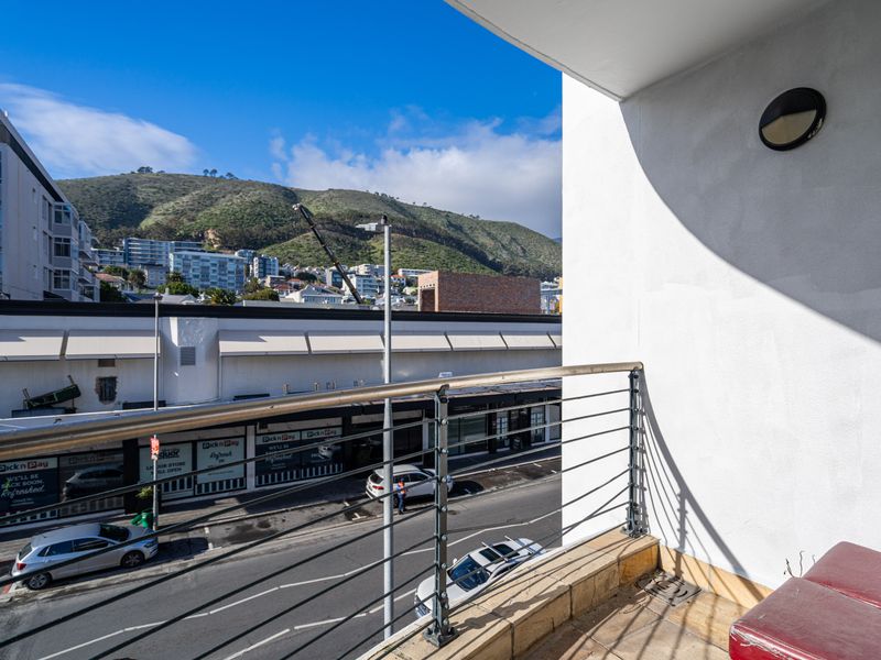 A private balcony featuring a stainless steel railing and mountain views, providing an elevated outdoor space overlooking the street.