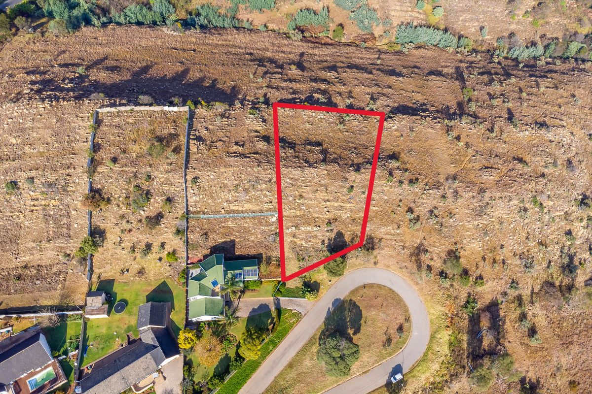 Aerial view of a vacant residential plot highlighted in red, situated in a developed estate with established road access and surrounding properties.
