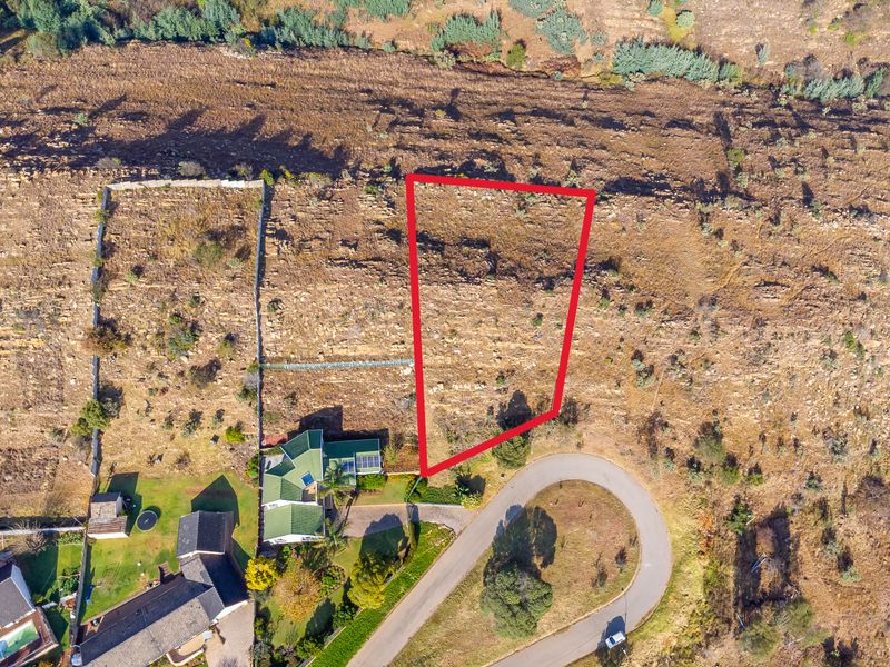 Aerial view of a vacant residential plot highlighted in red, situated in a developed estate with established road access and surrounding properties.
