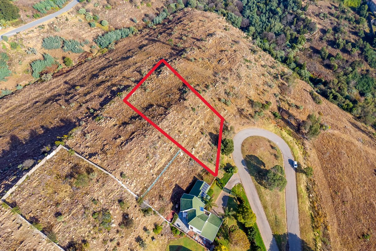 An aerial view of a vacant residential plot featuring sloped, rocky terrain with clear boundary markings, situated in a hillside neighborhood.