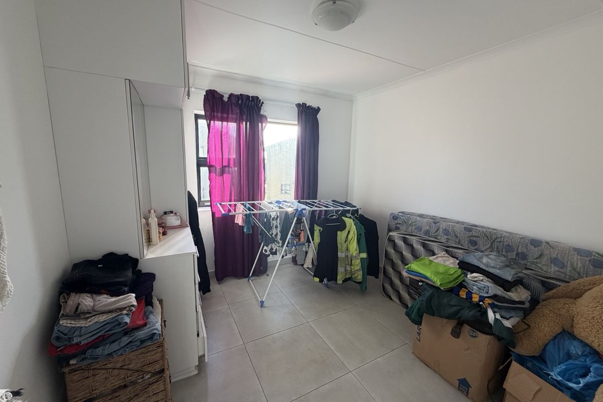 A bedroom featuring tiled flooring and built-in cupboards, offering a functional space ready for personalization.