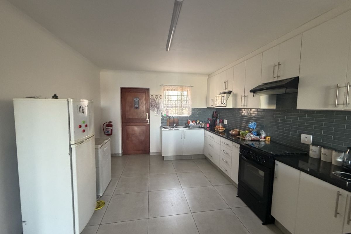 A functional kitchen featuring white cabinetry, dark countertops, a subway tile backsplash, and integrated cooking appliances with tiled flooring throughout.