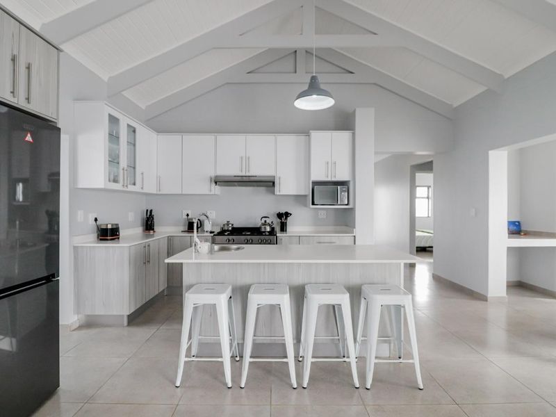 Modern kitchen featuring a central island, ample built-in cabinetry, vaulted ceilings, and high-quality finishes in a bright, open-plan layout.