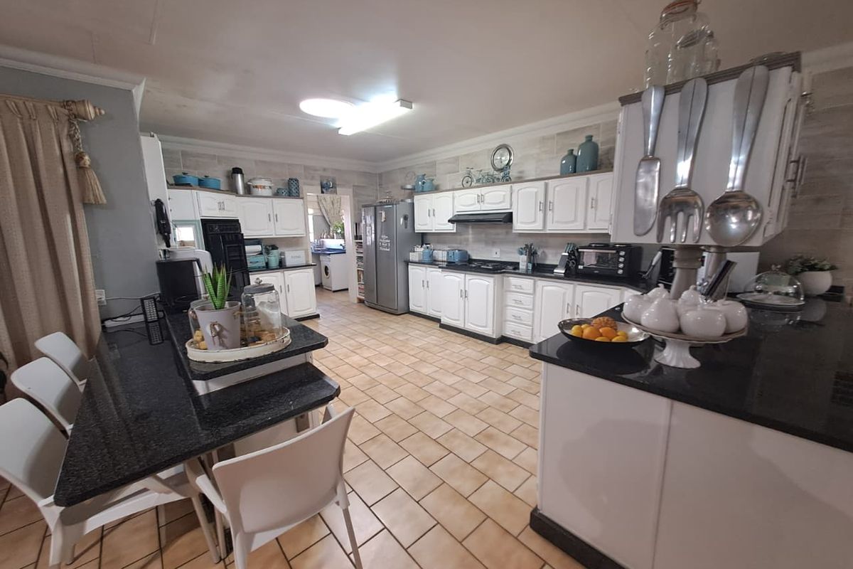 Spacious kitchen featuring white cabinetry, dark granite countertops, tiled flooring, and an integrated breakfast bar area.