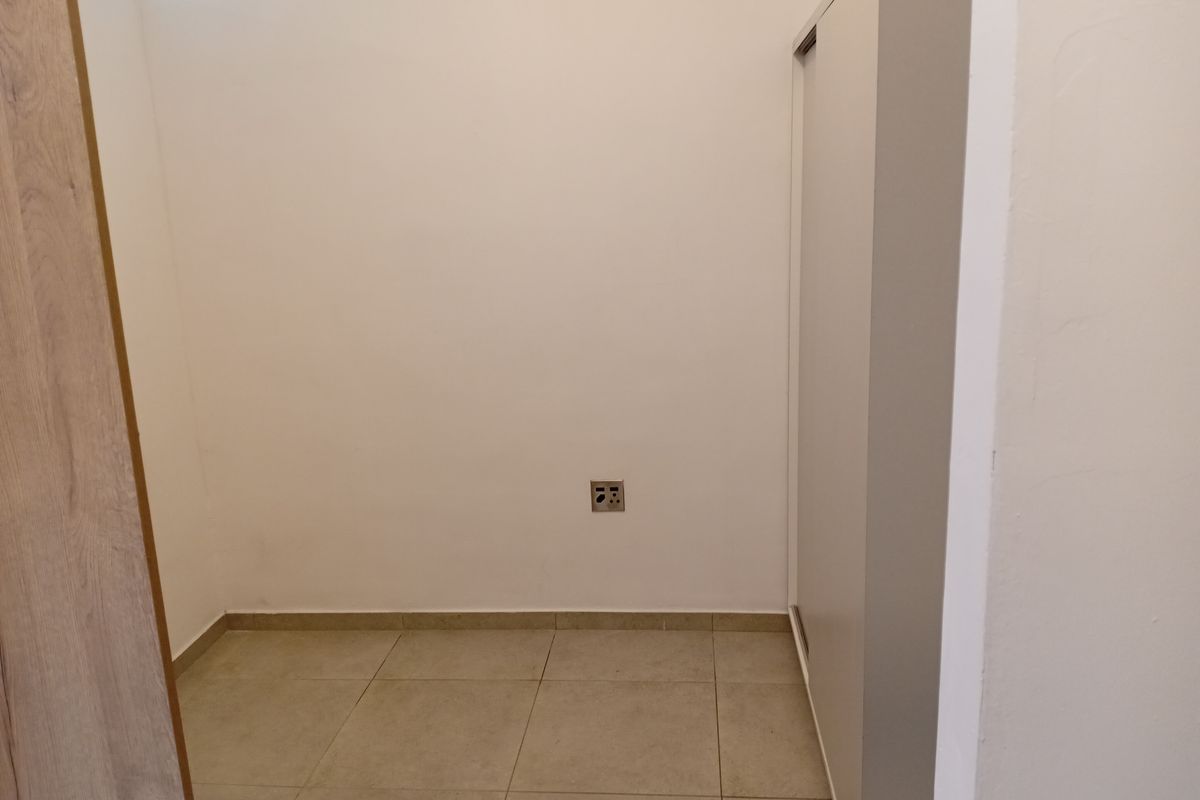 A clean, empty bedroom space featuring neutral tiled flooring and a built-in wardrobe, offering a blank canvas for personalization.