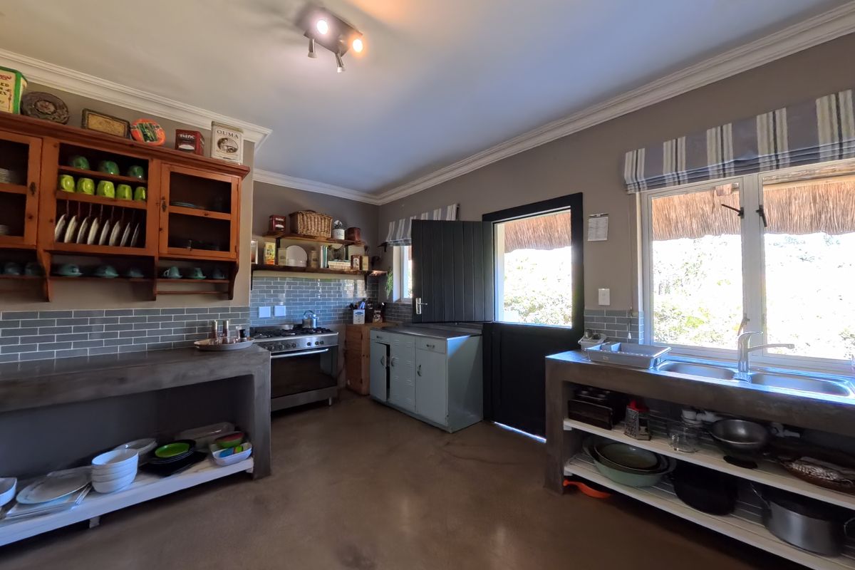 A rustic farmhouse kitchen featuring concrete countertops, a gas stove, double basin sink, and a stable door leading to the exterior.