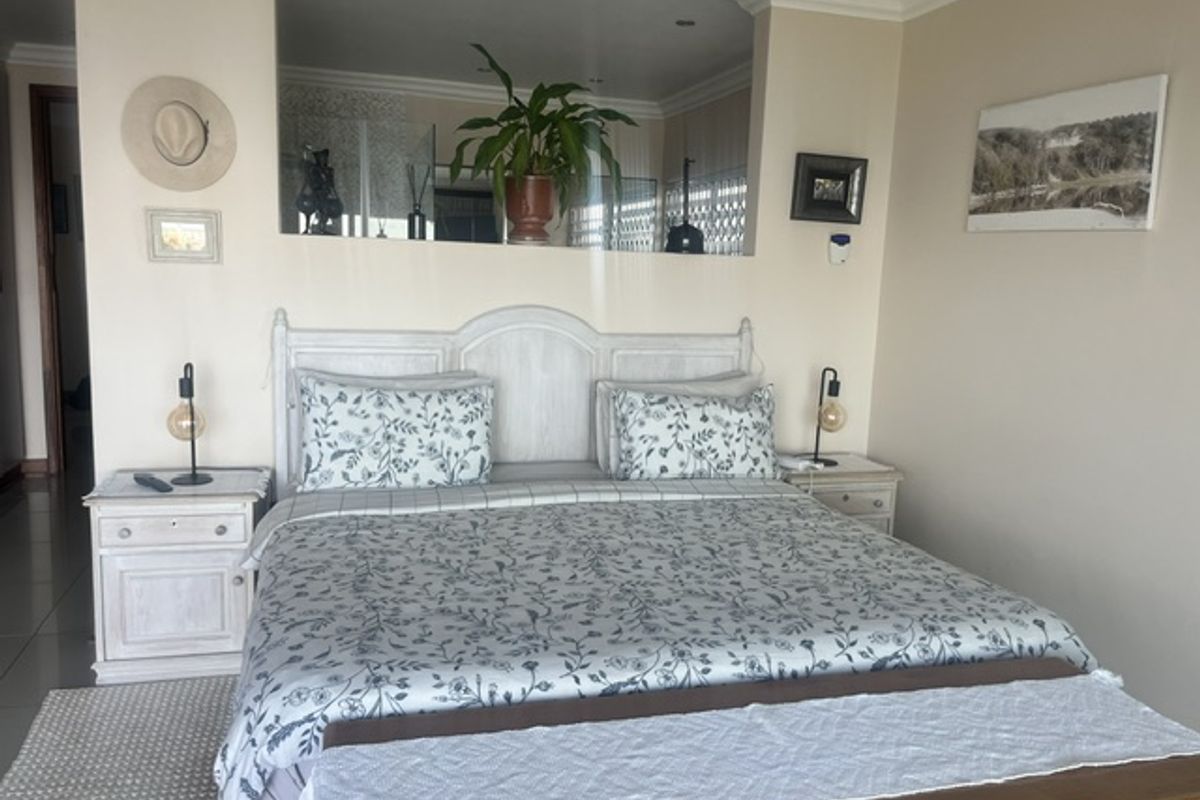 A well-maintained bedroom featuring tiled flooring, coving, and recessed ceiling lighting, with a partial wall partition creating a distinct sleeping area.