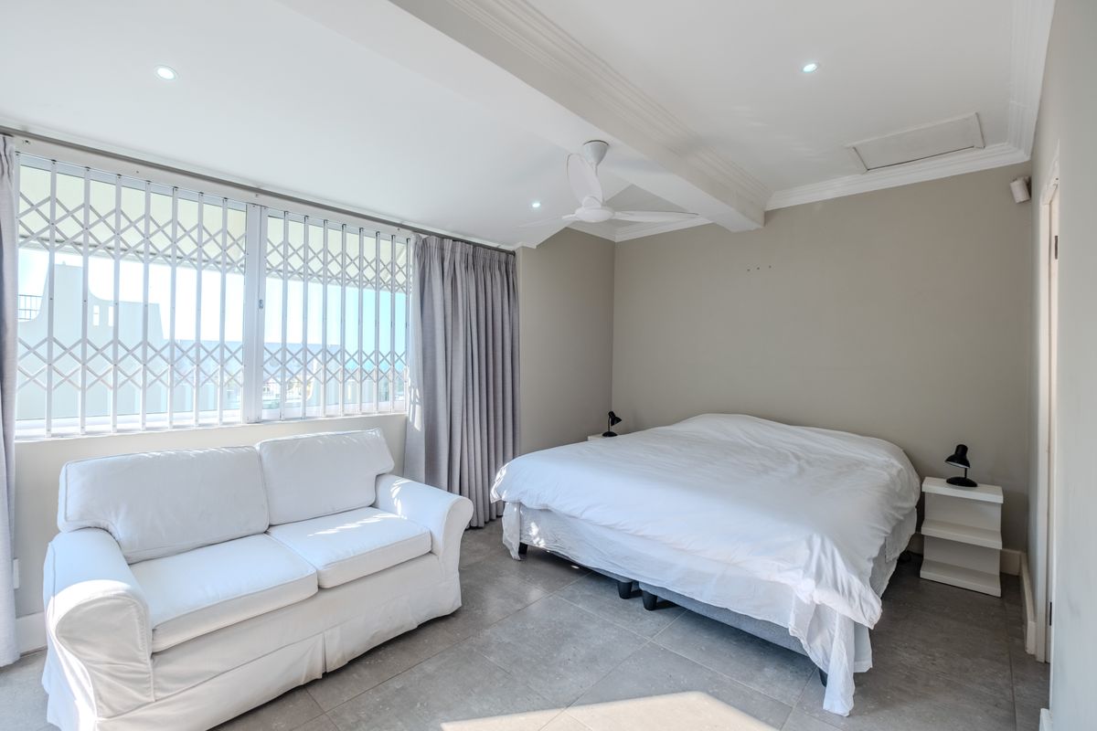 Spacious bedroom featuring tiled flooring, recessed downlights, a ceiling fan, and large windows fitted with security gates.