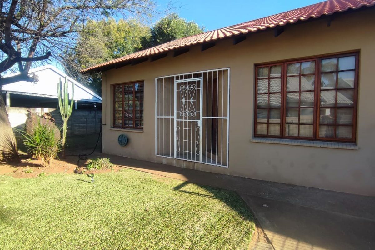 Rear exterior view of the townhouse featuring a tiled roof, timber-framed windows, and a secure entrance gate leading to a garden area.