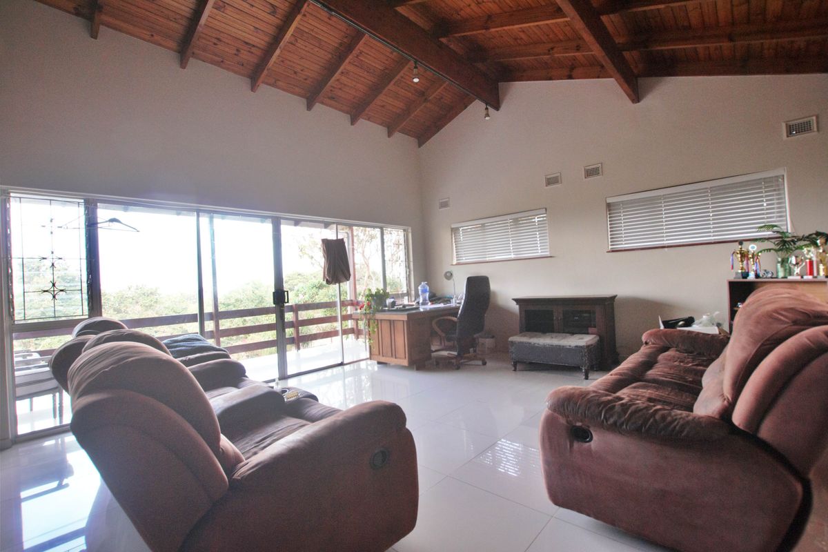 Spacious living area featuring high vaulted timber ceilings, large sliding glass doors leading to a balcony, and polished floor tiles.
