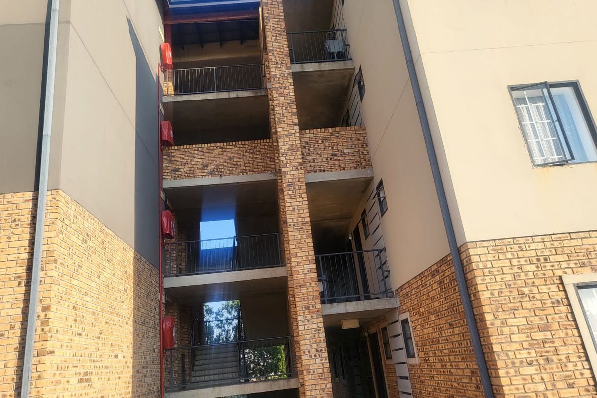 Exterior view of a multi-story apartment building featuring face brick facade, metal balustrades, and external stairwell access.