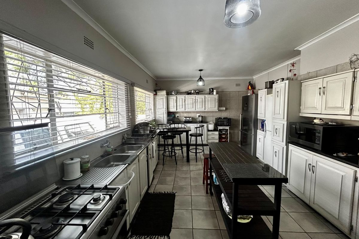 Spacious kitchen featuring gas stove, double sink, ample built-in cabinetry, and tiled flooring, offering a functional layout with significant potential for modern updates.