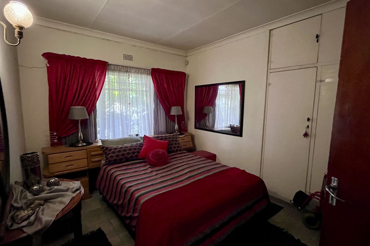 A bedroom featuring a built-in wardrobe, wall-mounted lighting, and a window with curtains.