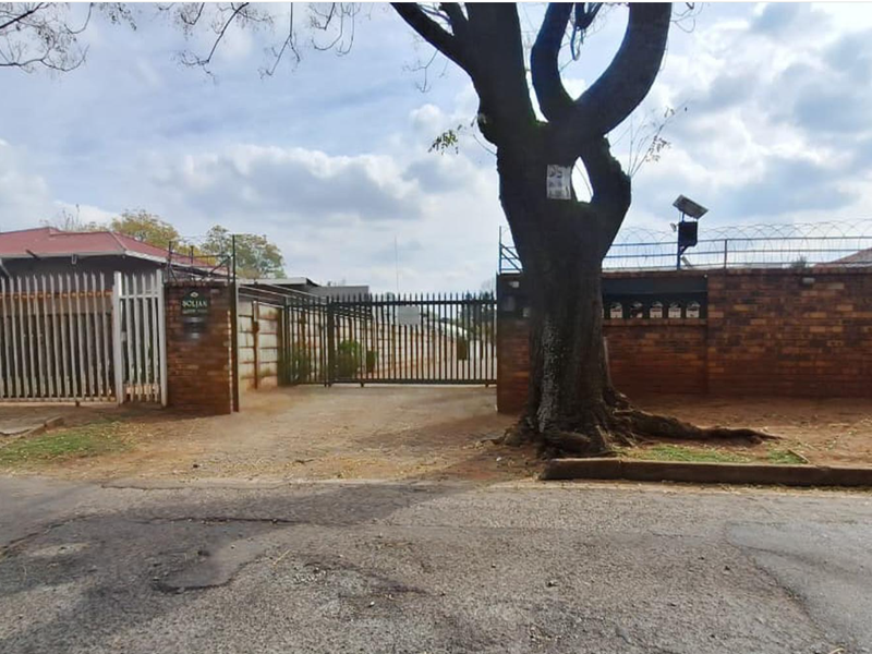 Street view of the property entrance featuring a brick boundary wall, metal security gate, and integrated post boxes.
