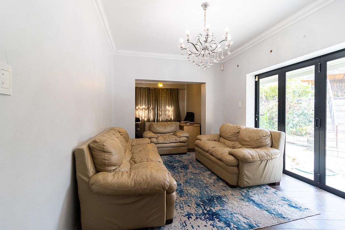 A living room featuring a crystal chandelier, tiled flooring, and black-framed sliding glass doors providing access to the outdoor area.