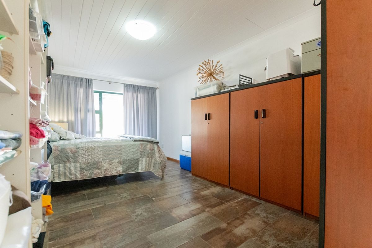 A bedroom featuring tiled flooring, a tongue and groove ceiling, and built-in wooden cupboards providing ample storage space.